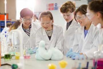 Surprised students conducting exploding foam scientific experiment in classroom laboratory