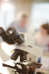 Male teacher helping girl student at microscope in laboratory classroom