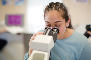 Girl student using microscope in classroom