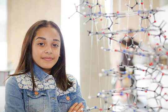 Portrait smiling girl student holding molecular model in laboratory classroom