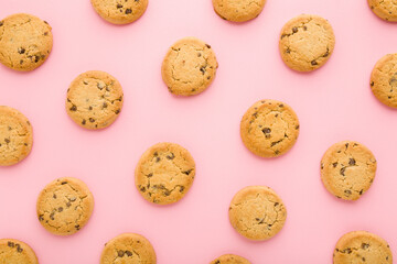 Dry cookies with chocolate pieces on light pink table background. Pastel color. Closeup. Sweet...