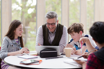 Obraz premium Male teacher and students using laptop at table