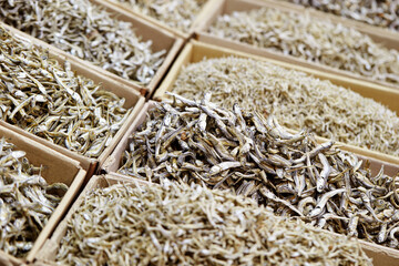 Various types of dried anchovies displayed in a traditional market