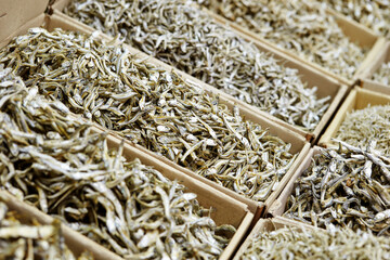 Various types of dried anchovies displayed in a traditional market