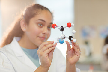 Curious girl student examining molecular structure in laboratory classroom
