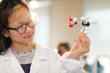 Portrait smiling, confident girl student holding molecular structure in laboratory classroom