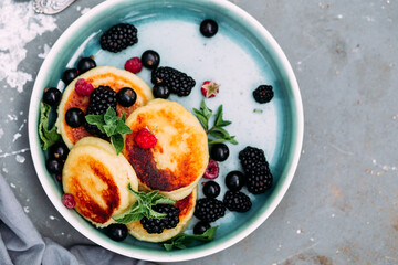 Sweet cottage cheese pancakes with raspberries, blackberries and currants in a plate close-up. Breakfast