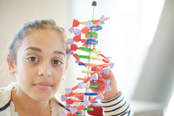 Girl student examining DNA model in classroom - Powered by Adobe