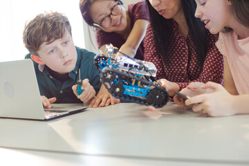 Female teacher and students playing with robot in classroom