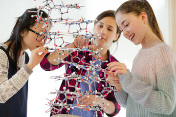 Curious girl students examining molecular structure in classroom