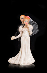 Bride and groom holding an old cake topper on a black background. Figurines for a wedding cake.