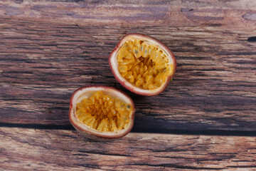 Two halves of cut passion fruit standing on coarse wooden table