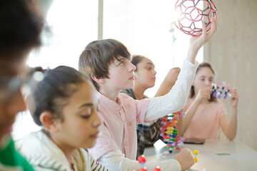 Confident students holding molecular structures in laboratory classroom