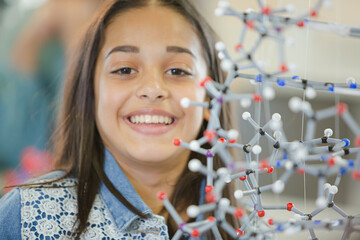 Portrait smiling girl student holding molecular model in laboratory classroom
