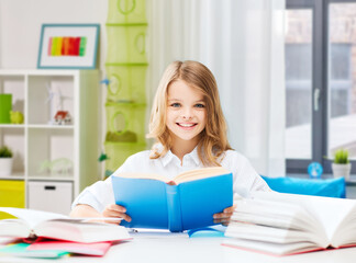 Fototapeta na wymiar education and school concept - happy smiling student girl reading book over home background