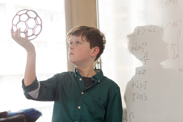Serious boy student holding molecular structure in classroom