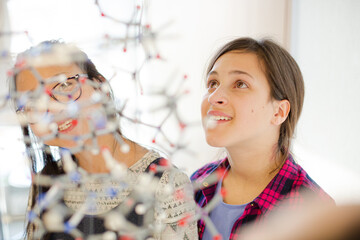 Curious girl students examining molecular structure in classroom