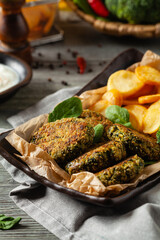 Vegetarian spinach and broccoli meatballs, served with yogurt dip and toasted potatoes. Front view.