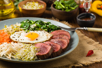 Korean beef with sprouts, spinach and fried egg.