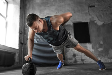 sport, bodybuilding, fitness and people concept - young man doing kettlebell push-ups in gym