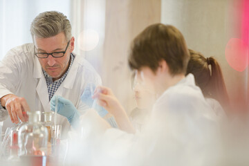 Male teacher and students conducting scientific experiment in laboratory classroom