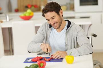 handsome man in wheelchair cuts veggetables