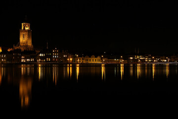 Fototapeta na wymiar A view on the houses and the Great Church in the City of Deventer, the Netherlands, at night with reflection in the water