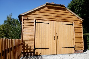 Pine log garage with lockable double wooden doors and picket fence