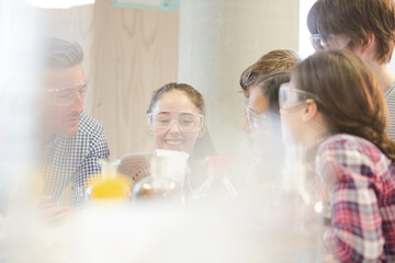 Male teacher and students watching chemical reaction, conducting scientific experiment in laboratory classroom