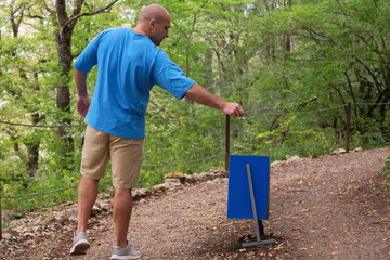 A man, a traveler throws trash into a trash can outdoors, in the mountains. Recycling, green approach concept. Keep the ground clean.