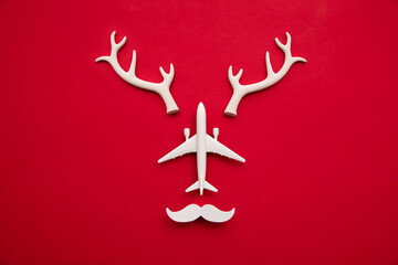 Festive christmas travel reindeer face made from airplane and antlers on a red background