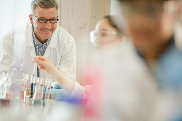 Male teacher and girl students conducting scientific experiment in laboratory classroom