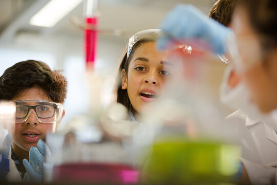 Students examining liquid in test tube, conducting scientific experiment in laboratory classroom