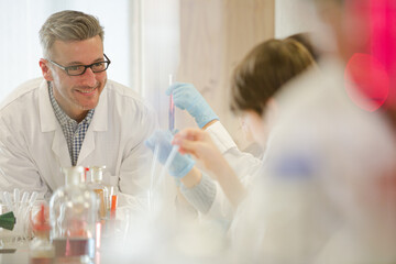 Male teacher and students conducting scientific experiment in laboratory classroom