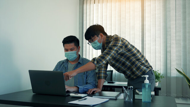 Asian colleague stood at the office and analyzed corporate data while wearing a face mask during COVID-19.