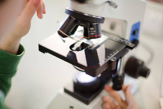 Boy student using microscope, conducting scientific experiment