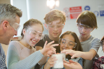 Curious, smiling students watching chemical reaction, conducting scientific experiment in laboratory classroom