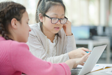 Girl students using laptop in library