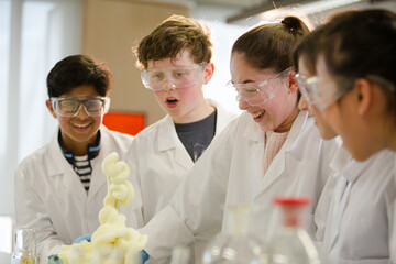 Surprised students conducting scientific experiment, watching chemical reaction in classroom laboratory