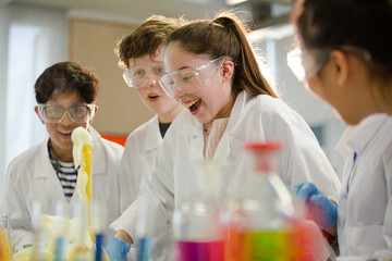 Surprised students conducting scientific experiment, watching chemical reaction in classroom laboratory