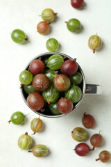 Cup of ripe gooseberry on white textured background