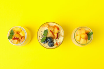 Glass jars with peach yogurt on yellow background