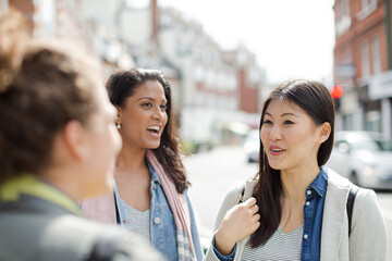 Smiling female friends talking on urban street