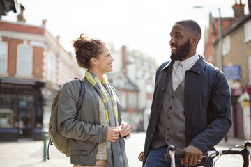 Smiling businessman with bicycle and woman on urban street