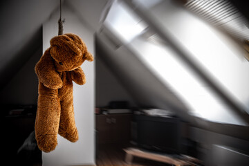 A teddy bear hanging in a noose in the attic room