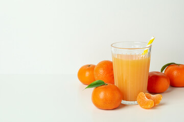 Glass of mandarin juice and ingredients on white background
