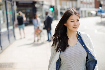 Serious, pensive young woman walking on urban street