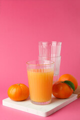 Board with mandarin juice and ingredients on pink background