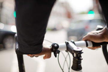 Fototapeta premium Hands on man on bicycle handlebars, commuting on sunny urban street