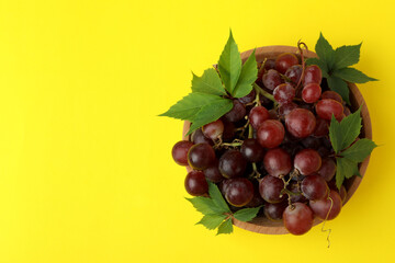 Bowl ripe grape on yellow background, space for text